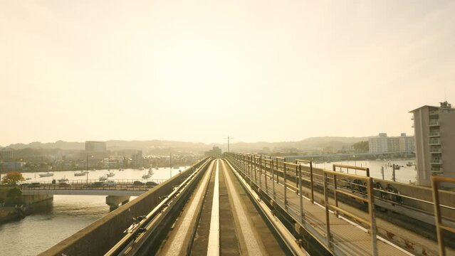 4K Point of view landscape of Skytrain running on railway track passing through Tokyo bay in Japan at sunset. Urban transportation and railroad industry concept.