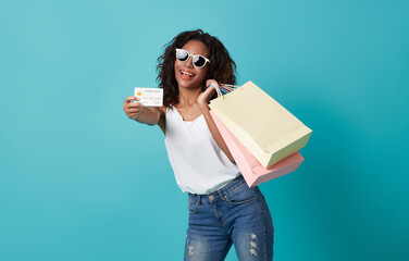 happy smiling young woman showing credit card for shopping and payment  isolated on blue studio...