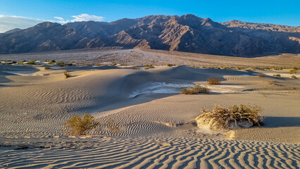 Panoramic view on Mesquite Flat Sand Dunes in Death Valley National Park, California, USA. Looking at dry Mojave desert on hot sunny summer day with Amargosa Mountain Range in the back. Landscape