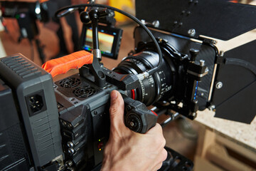 Fototapeta na wymiar The hand of a cameraman controls a professional movie camera on a film set