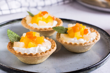 Tartlets with whipped cream and canned pineapple and papaya on a plate