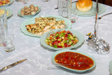 Different salads on white plates staying on banquet table. Sliced corn, tomato, pepper, cucumber, cabbage mushrooms healthy vegetarian dishes. Selective focus