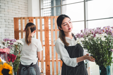 Two female employees meticulously arrange flowers for customers in a flower shop.