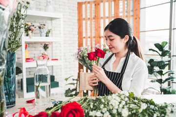 Young florist is meticulously trimming flowers to make a beautiful vase in a flower shop.