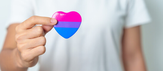 Bisexuality Celebrate Day and LGBT pride month,  LGBTQ+ or LGBTQIA+ concept. Hand holding purple,...