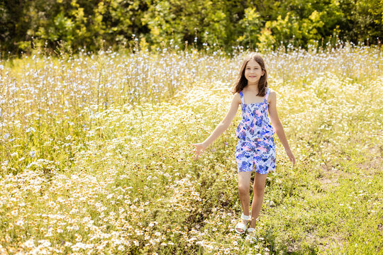 Cute teenage girl walking in a summer flower field
