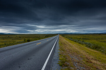 Epic cloudy landscape of an empty highway through the tundra of  Norway