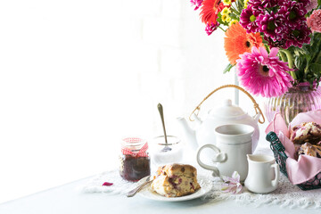 A bright setting of tea and scones with copy space to the left.