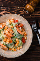 Italian kitchen Caesar salad with shrimps, parmesan cheese, lettuce, cherry tomatoes and croutons.