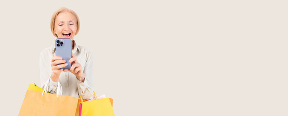 Old female use mobile phone using smart phone for shopping online carry shopping bags isolated over beige pastel background and copy space Happy Smiling elderly woman purchasing online through phone