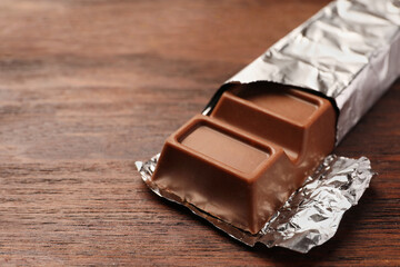 Tasty chocolate bar on wooden table, closeup. Space for text