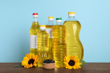 Bottles of cooking oil, sunflowers and seeds on wooden table