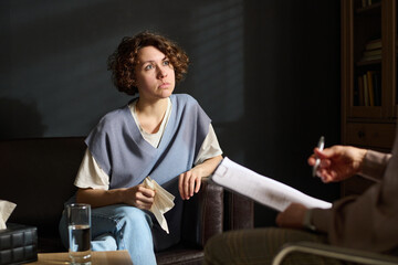 Upset young female patient of psychologist looking at counselor giving her piece of advice or...