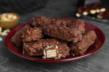 Plate of tasty chocolate bars with caramel on light grey table