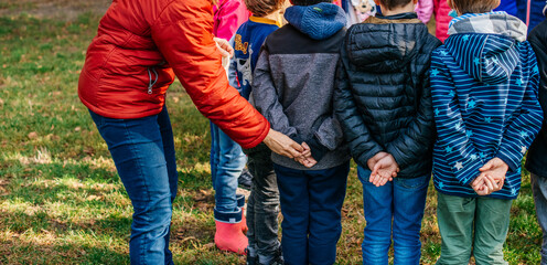 Close-up of children holding their hands behind their backs in the park, the teacher puts an object in the hand. Children's outdoor games