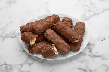 Tasty chocolate bars with caramel on white marble table, top view