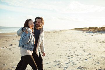 Young adult couple walking on a beach during cold weather