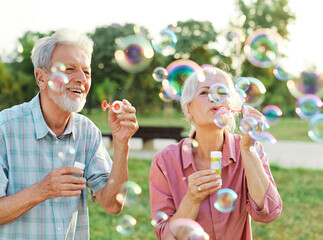 woman man senior couple  together elderly active happy retirement bubble soap blowing fun blow vitality bonding park outdoor leisure park fun - Powered by Adobe