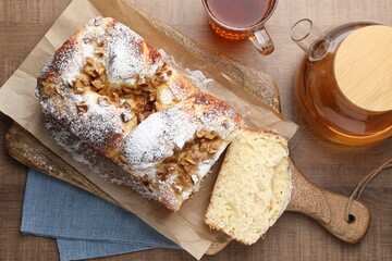 Delicious yeast dough cake and cup of tea on wooden table, flat lay