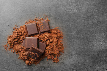 Delicious dark chocolate and cocoa powder on grey table, flat lay. Space for text