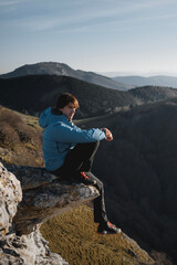 Boy looking at the horizon sitting on a rock at sunset in the mountains of duranguesado in vizcaya,...