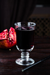 Freshly squeezed pomegranate juice in a glass on dark background.