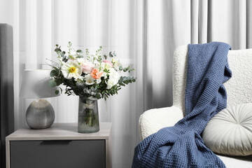 Bouquet of beautiful flowers near armchair indoors © New Africa