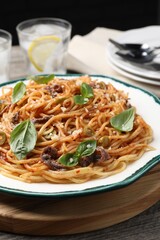 Delicious pasta with anchovies, tomato sauce and basil on wooden table