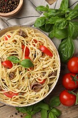 Delicious pasta with anchovies, tomatoes and spices on wooden table, flat lay