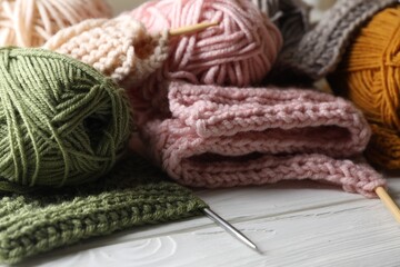 Fototapeta na wymiar Balls of soft yarns, knitting and needles on white wooden table, closeup