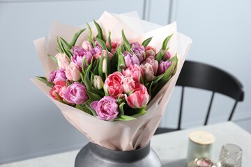 Vase with bouquet of beautiful tulips on table indoors, closeup