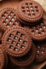 Tasty chocolate sandwich cookies with cream on plate, closeup