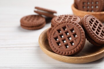 Tasty chocolate sandwich cookies with cream on white wooden table, closeup. Space for text