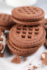 Tasty chocolate sandwich cookies with cream on light grey table, closeup