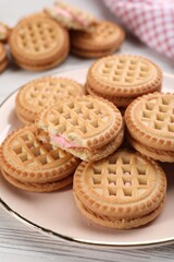 Tasty sandwich cookies with cream on white wooden table, closeup