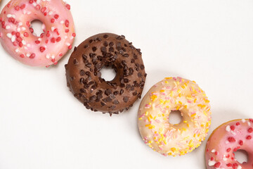 Four donuts in a row - white, pink and chocolate on a white background top view