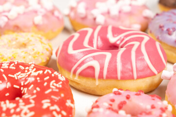Donuts with red and pink glaze, side view. Lots of donuts, sweet and delicious food