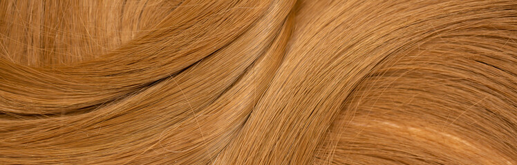 Obraz premium Red hair close-up as a background. Women's long orange hair. Beautifully styled wavy shiny curls. Hair coloring bright shades. Hairdressing procedures, extension.