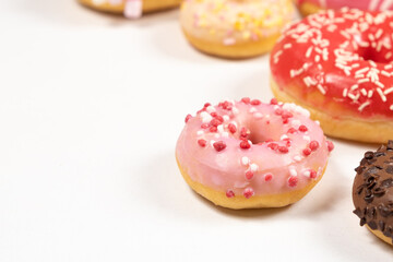 Many different donuts on a white background top view, pink, white and chocolate donuts of different sizes