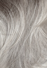 Blond hair close-up as a background. Women's long blonde hair. Beautifully styled wavy shiny curls. Hair coloring. Hairdressing procedures, extension. White hair