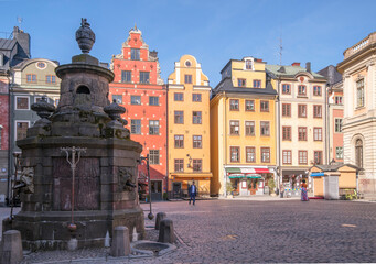The square Stortorget, color full 1600s houses, old fresh water pump and the Nobel Museum, a sunny day in Stockholm
