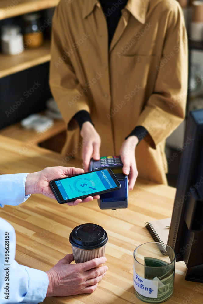 Poster close-up of cafe clerk in uniform holding terminal during contactless payment while female client wi