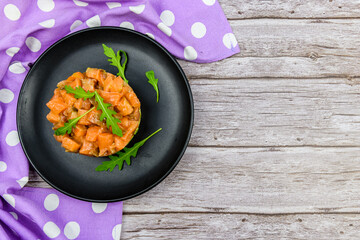 Salmon tartare with arugula on a wooden background. Top view