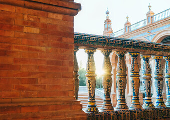 The Plaza de España galleries lited up with evening sunlight. Painted balusters view on Spain Square, Andalusia, South Spain. - obrazy, fototapety, plakaty