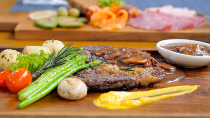 Delicious grilled ribeye beef steak served with vegetables on a rustic wooden board. Gourmet BBQ grilled Wagyu Rib Eye beef steak sliced and presented on a wooden plate with herbs and spices.