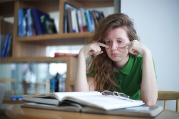 tired overworked, exhausted young woman in glasses college or university student is study hard in...