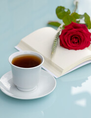 a cup of coffee or tea, a rose on a book, a romantic morning, concept of celebrating Sant Jordi in Spain, book day, gifts for April 23