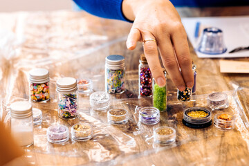 Jewelry workshop with epoxy resin. Close-up of a woman's hand choosing decorations for her jewelry.
