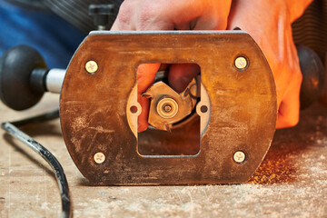 Worker's hands install a cutter for the production of grooves on a manual electric milling cutter