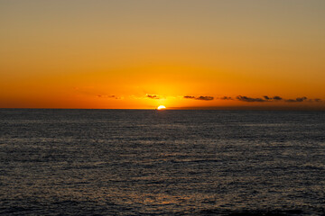 Obraz premium Beautiful, red orange dawn on the mediterranean sea. The rays of the sun through the fog. The blue sky over the mediterranean sea, the morning comes, the sun is reflected in the water.